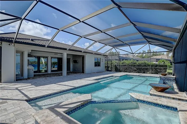 View of swimming pool featuring a lanai, an in ground hot tub, and a patio area