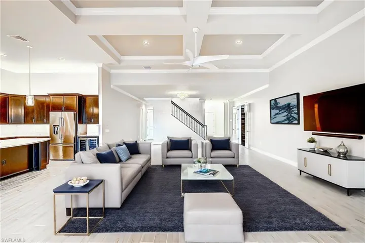 Living room featuring coffered ceiling, light hardwood / wood-style flooring, beam ceiling, crown molding, and ceiling fan