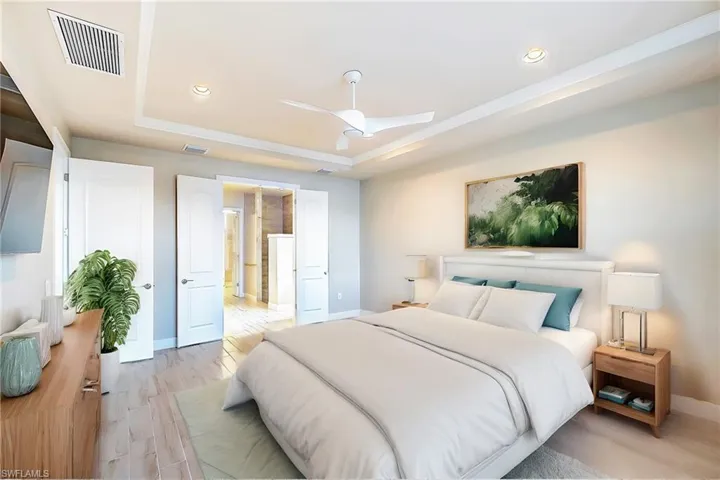 Bedroom featuring ceiling fan, a tray ceiling, and light hardwood / wood-style floors