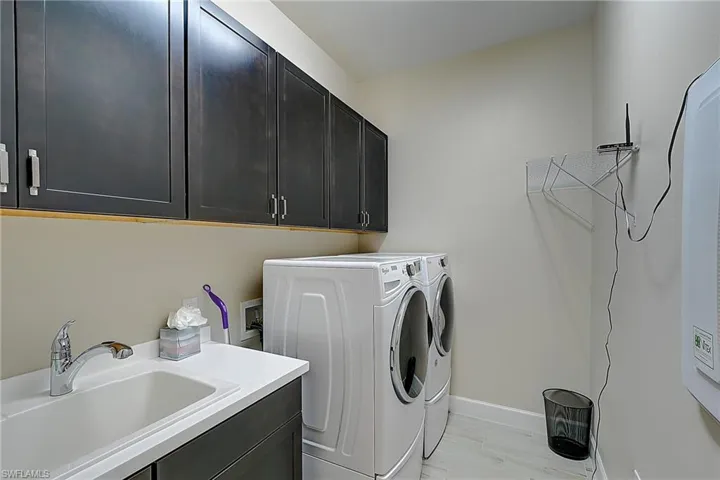 Washroom with washer and dryer, light hardwood / wood-style floors, cabinets, and sink