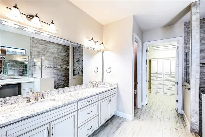 Bathroom featuring tiled shower and vanity