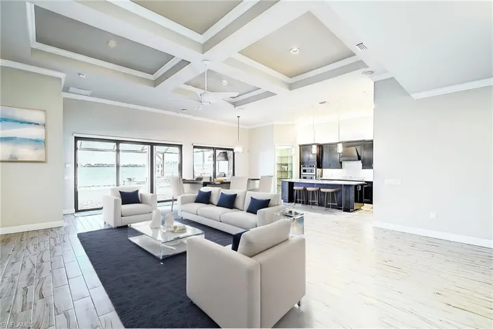 Living room with light hardwood / wood-style flooring, coffered ceiling, ornamental molding, and ceiling fan