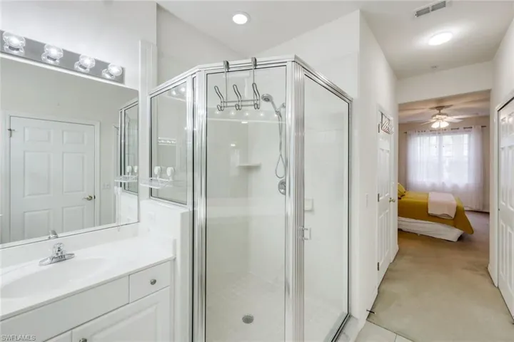 Ensuite bathroom featuring a shower stall, vanity, ceiling fan, and recessed lighting