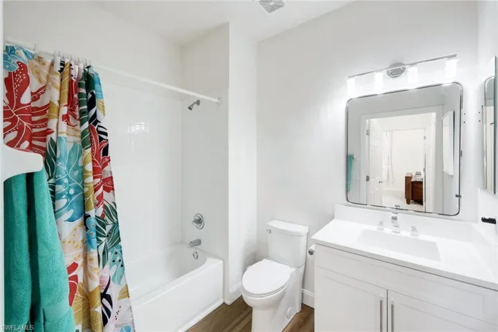 Bathroom featuring vanity, shower / bath combo with shower curtain, and dark wood-style floors