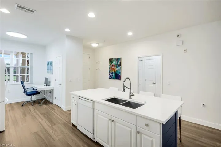 Kitchen featuring white cabinetry, an office area, white appliances, a kitchen island with sink, and dark wood-type flooring