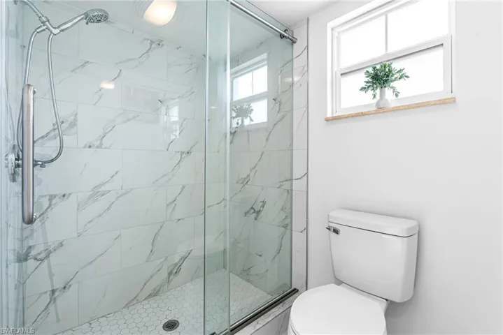 Full bathroom featuring a marble finish shower and toilet