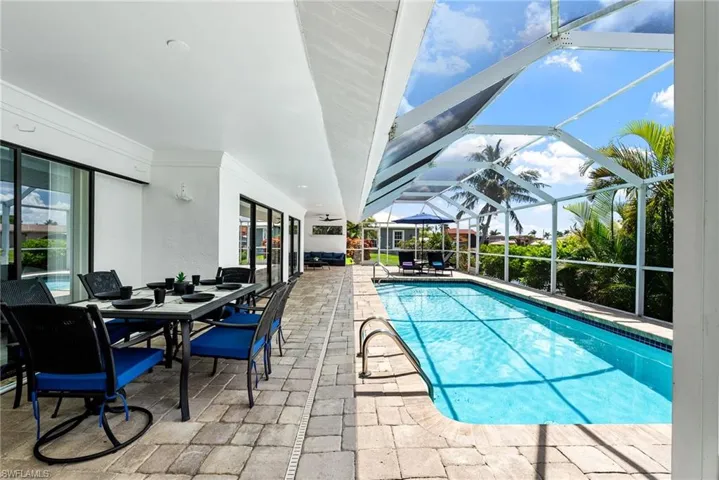 Outdoor pool with a patio, outdoor dining space, a sunroom, and glass enclosure