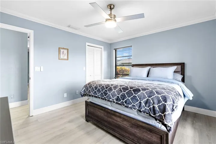 Bedroom featuring ornamental molding, a closet, light wood-style flooring, and ceiling fan