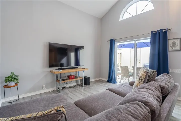 Living room with high vaulted ceiling and light wood-type flooring