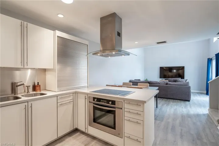 Kitchen featuring oven, light hardwood / wood-style flooring, island range hood, and kitchen peninsula