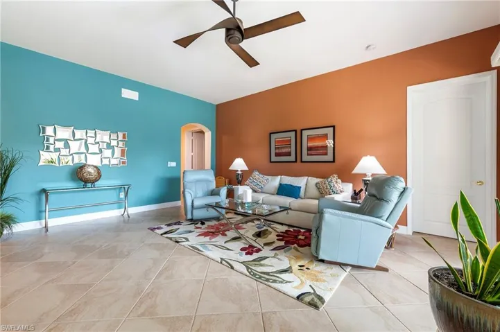 Living area featuring arched walkways, ceiling fan, and light tile patterned floors