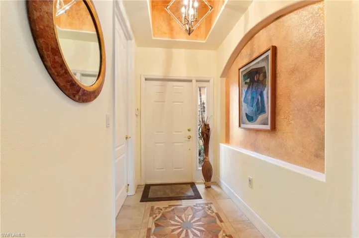 Entryway with inlaid floor details, a textured wall, and a chandelier