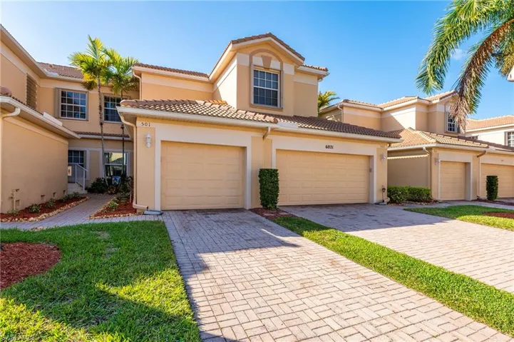 Mediterranean / spanish-style carriage home with stucco siding, decorative driveway, and a tiled roof