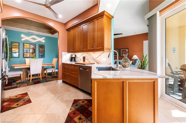 Kitchen featuring ceiling fan, wood finish cabinets, light stone counters, and decorative backsplash