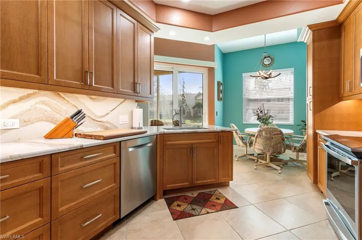 Kitchen with wood finish cabinets, stainless steel appliances, healthy amount of natural light, and light tile patterned flooring