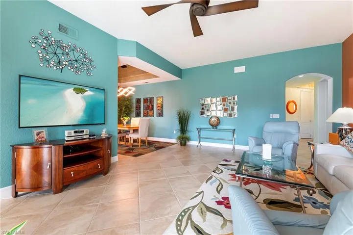 Living area featuring ceiling fan, arched walkways, and light tile patterned floors