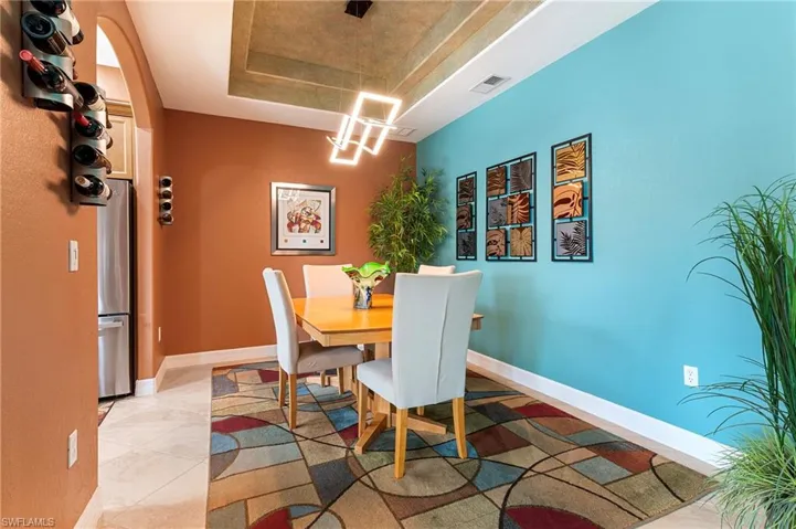 Dining space featuring a tray ceiling, light tile patterned floors, and suspended lighting