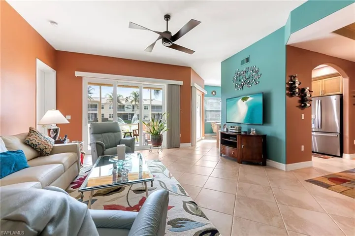 Living area with arched walkways, a ceiling fan, and light tile patterned floors