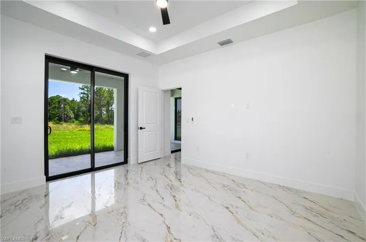Unfurnished room featuring a tray ceiling, marble tiled flooring, a ceiling fan, and recessed lighting