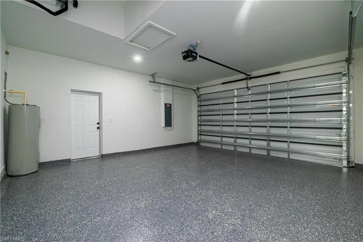 Garage featuring water heater, a garage door opener, and electric panel