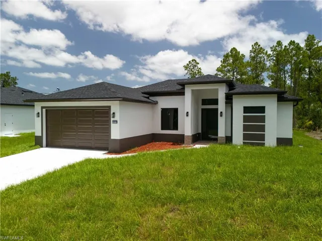 Prairie-style home featuring an attached garage, stucco siding, driveway, and a front lawn