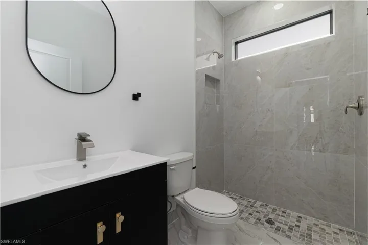 Bathroom with vanity, a tile shower, and marble finish floors