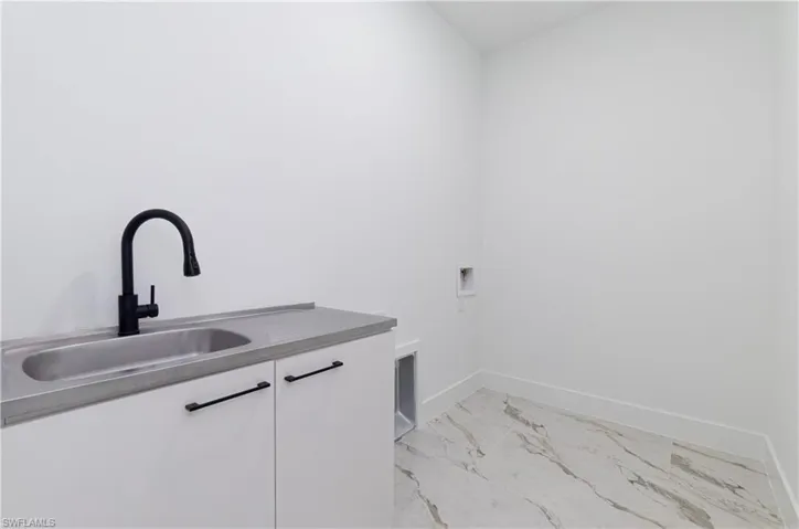Laundry area featuring cabinet space, washer hookup, and light marble finish floors