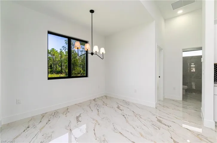 Spare room featuring a chandelier and marble finish flooring