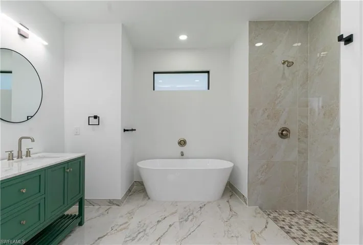 Full bathroom with vanity, a tile shower, a freestanding tub, marble finish flooring, and recessed lighting
