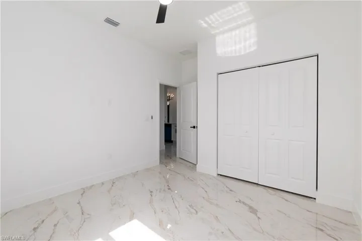 Unfurnished bedroom featuring a closet, marble finish flooring, and a ceiling fan