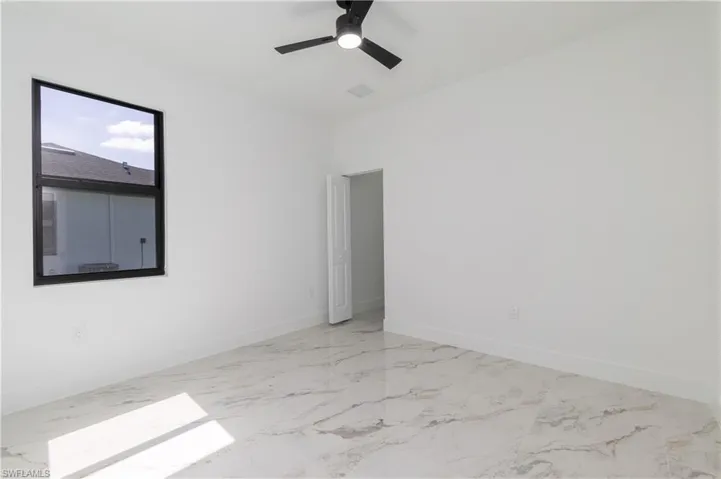 Spare room featuring marble finish floors and ceiling fan