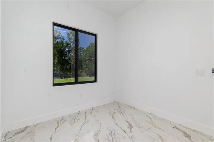 Spare room featuring baseboards and marble finish flooring