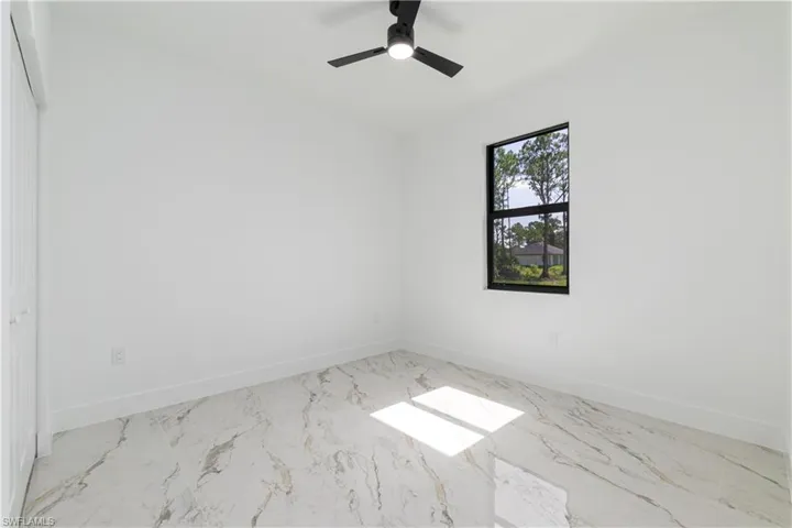 Spare room with marble finish floors and ceiling fan
