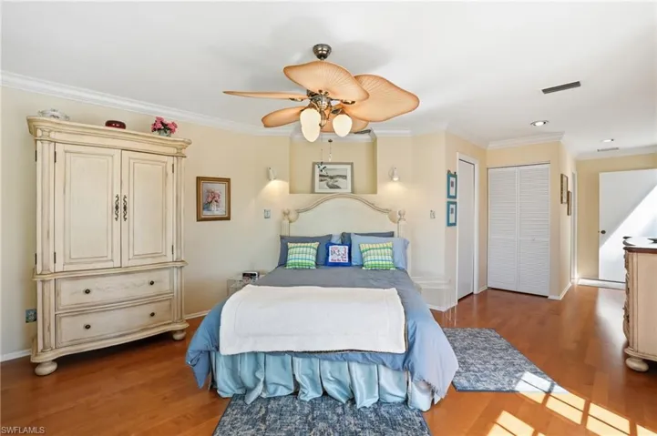 Bedroom with crown molding, wood finished floors, ceiling fan, and a closet