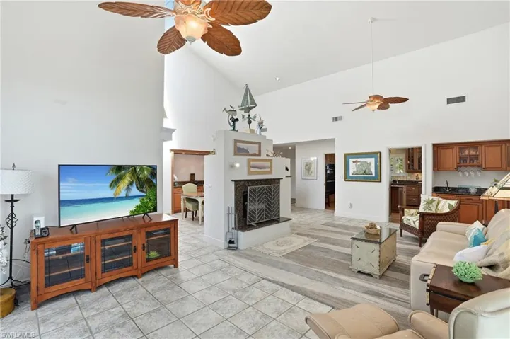 Living area featuring a ceiling fan, vaulted ceiling, and light tile patterned flooring
