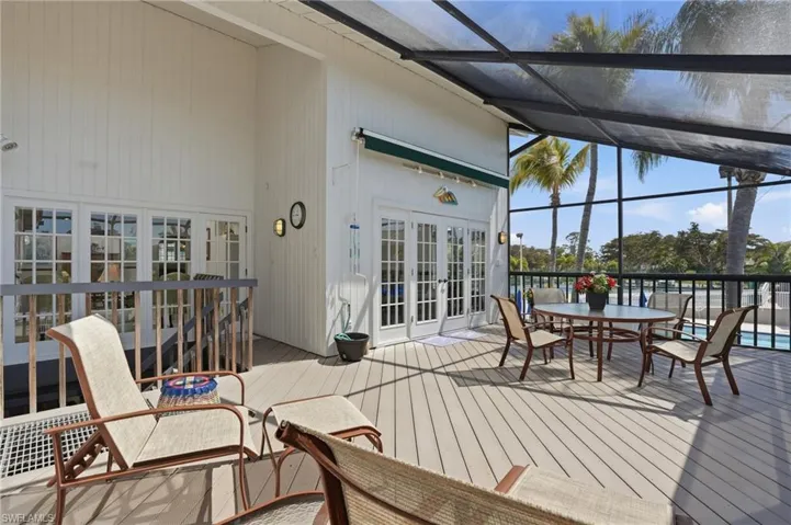 Wooden terrace featuring a sunroom, a lanai, french doors, and outdoor dining space