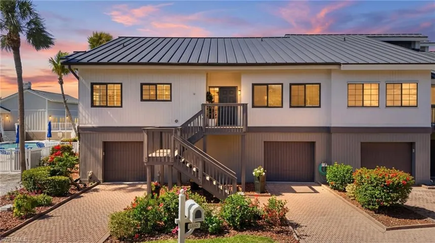 View of front facade with decorative driveway, a garage, and a standing seam roof
