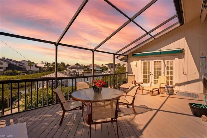 Wooden deck with french doors, a sunroom, a lanai, a residential view, and outdoor dining area