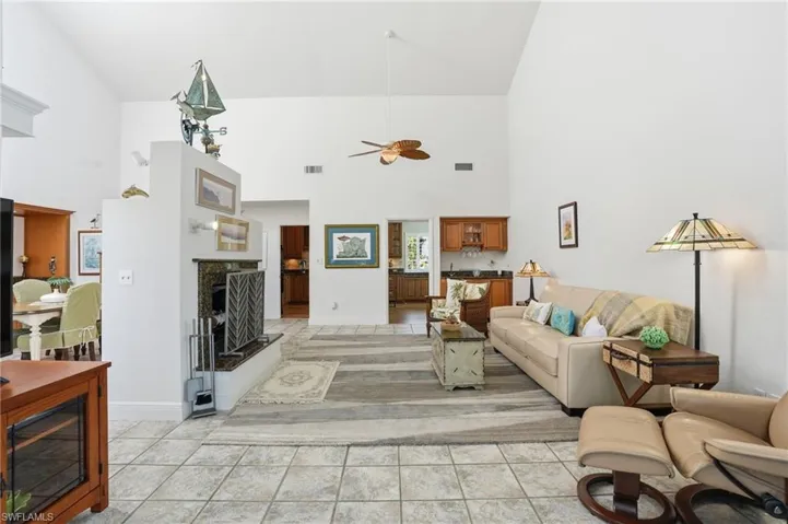 Living area featuring a ceiling fan, light tile patterned floors, lofted ceiling, and a fireplace