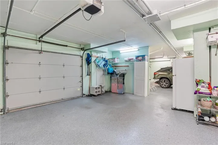 Garage featuring freestanding refrigerator and a garage door opener