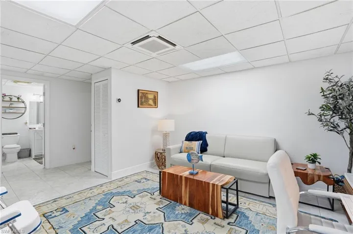 Living room with a paneled ceiling and light tile patterned floors