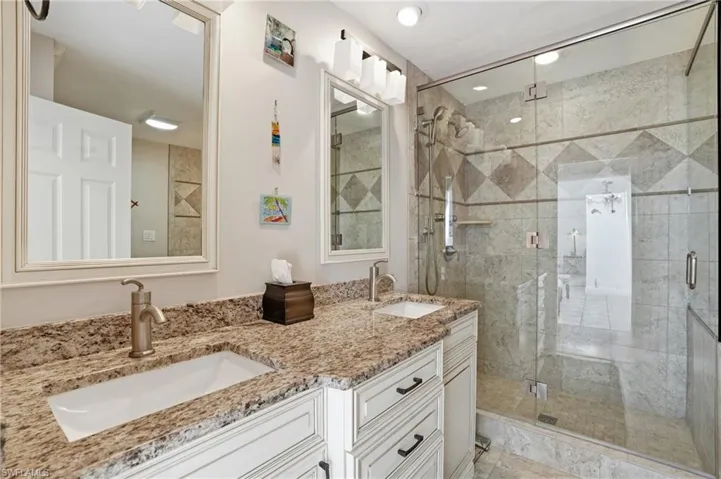 Full bath featuring double vanity and a shower stall
