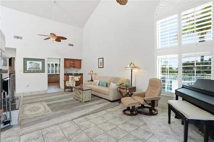 Living area with ceiling fan, a fireplace, light tile patterned floors, and lofted ceiling