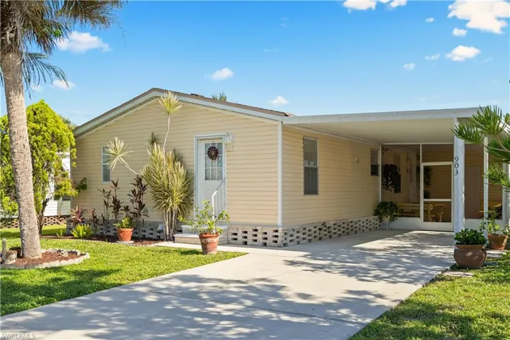 Manufactured / mobile home with concrete driveway, a carport, and a front lawn