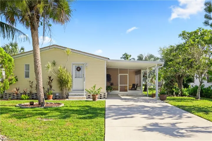 Manufactured / mobile home with concrete driveway, entry steps, a front yard, and a carport