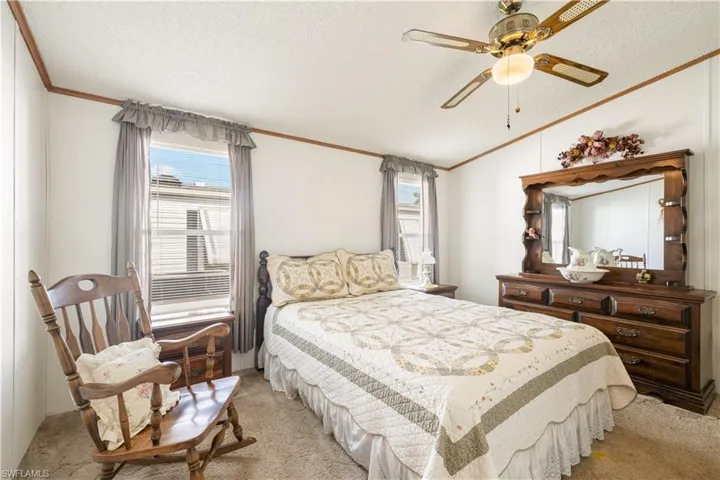Bedroom with ornamental molding, light carpet, multiple windows, lofted ceiling, and a textured ceiling