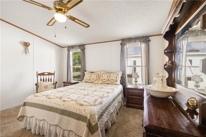 Bedroom with carpet flooring, crown molding, a textured ceiling, and a ceiling fan