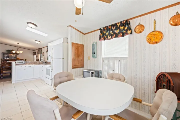 Dining area with wallpapered walls, a textured ceiling, a chandelier, crown molding, and ceiling fan