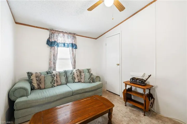 Living room featuring crown molding, light colored carpet, ceiling fan, vaulted ceiling, and a textured ceiling