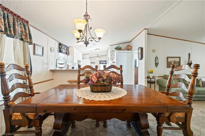 Dining area featuring a textured ceiling, a chandelier, lofted ceiling, crown molding, and carpet
